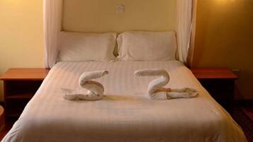 Quarto de hotel com uma cama, duas mesas de cabeceira e uma cortina.