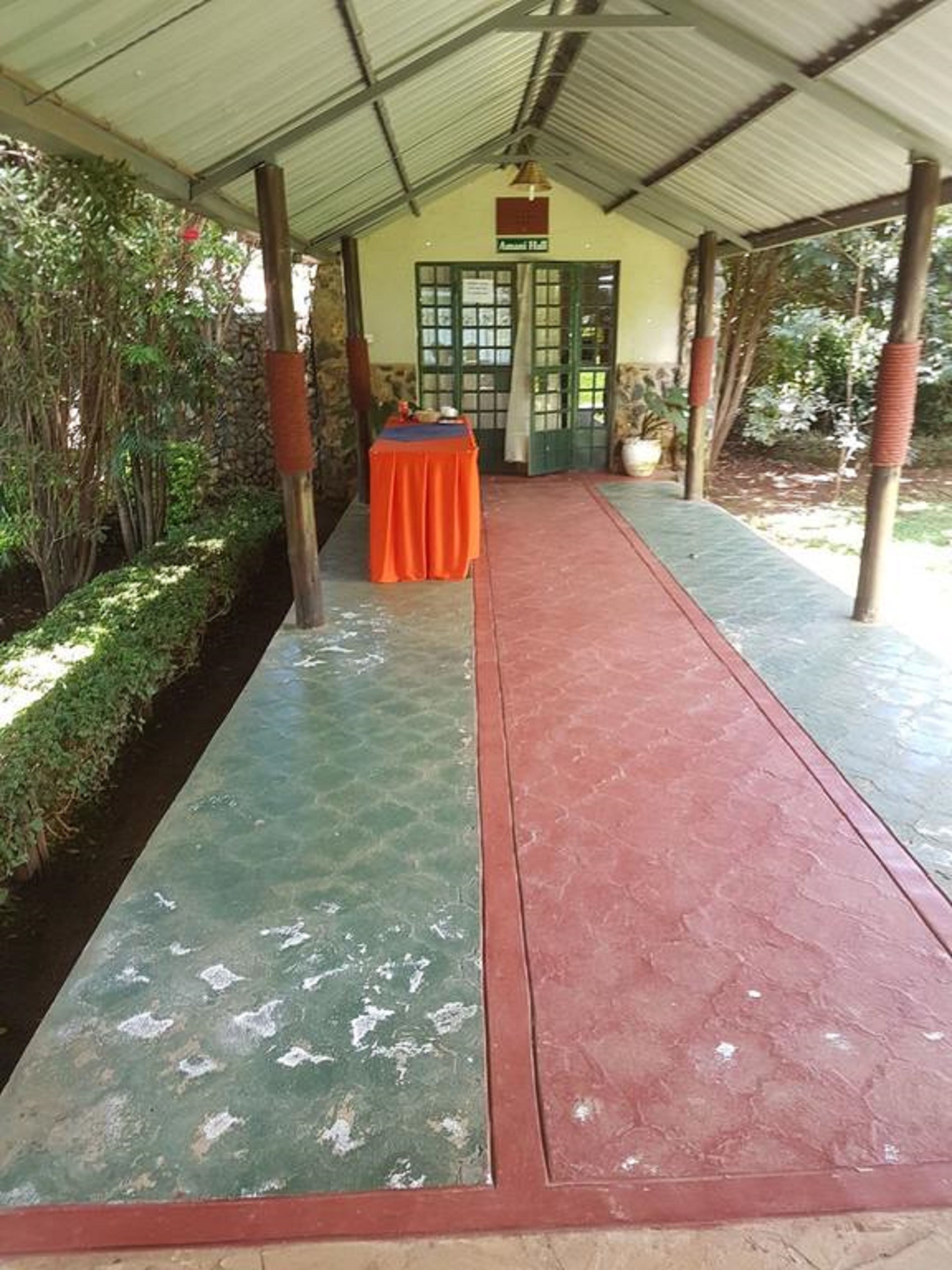 Un pasillo cubierto con una mesa dispuesta para comer, que lleva a un edificio con una puerta verde.