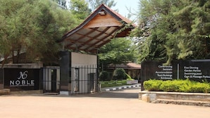 The entrance to the Noble Hotel & Conference Centre, featuring a gated entrance, a covered roof, and a sign listing amenities such as conference rooms, accommodation, and a swimming pool. - The Noble Hotel and Conference Center (Eldoret)