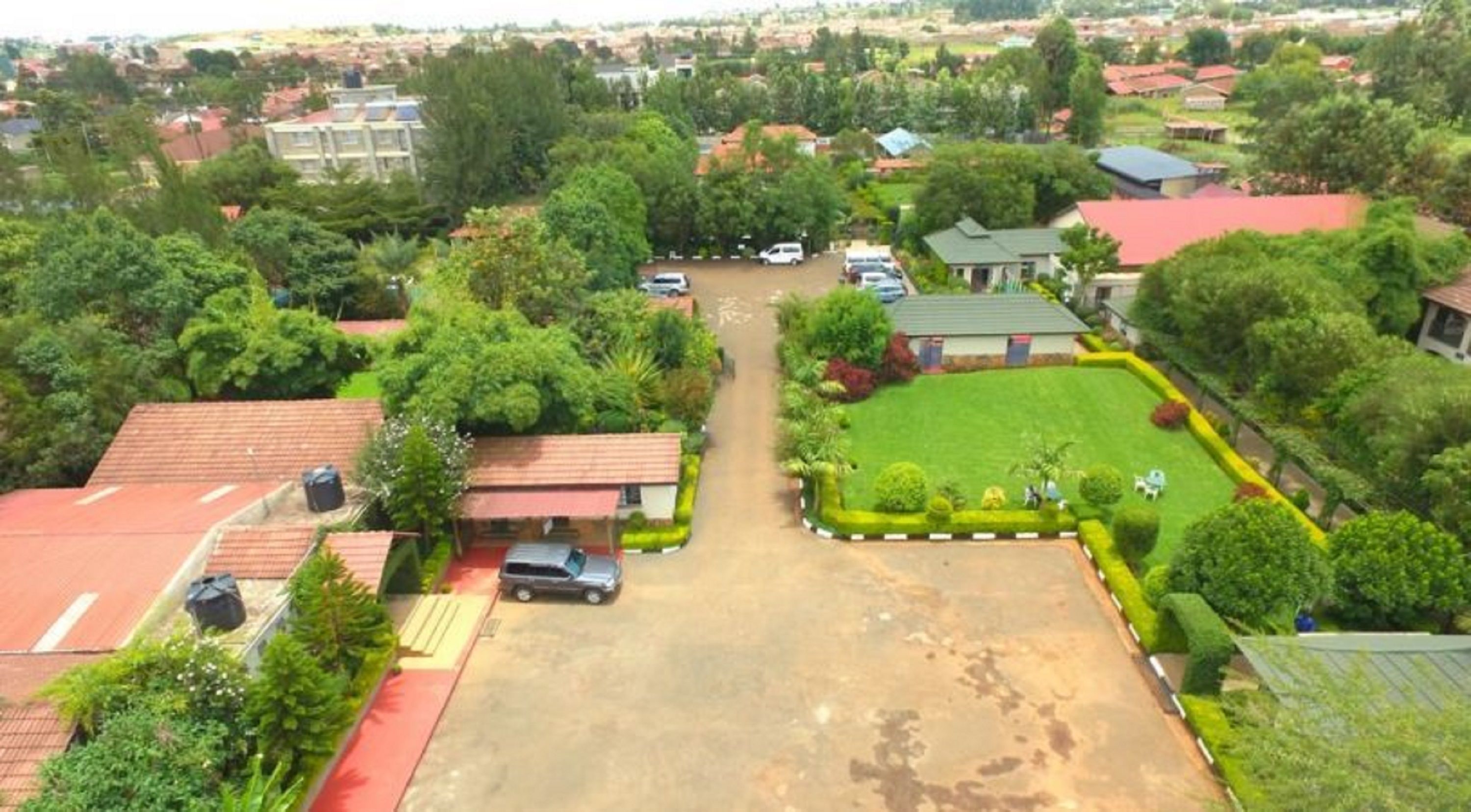 An aerial view of a residential area with houses, a central green space, and a parking lot.