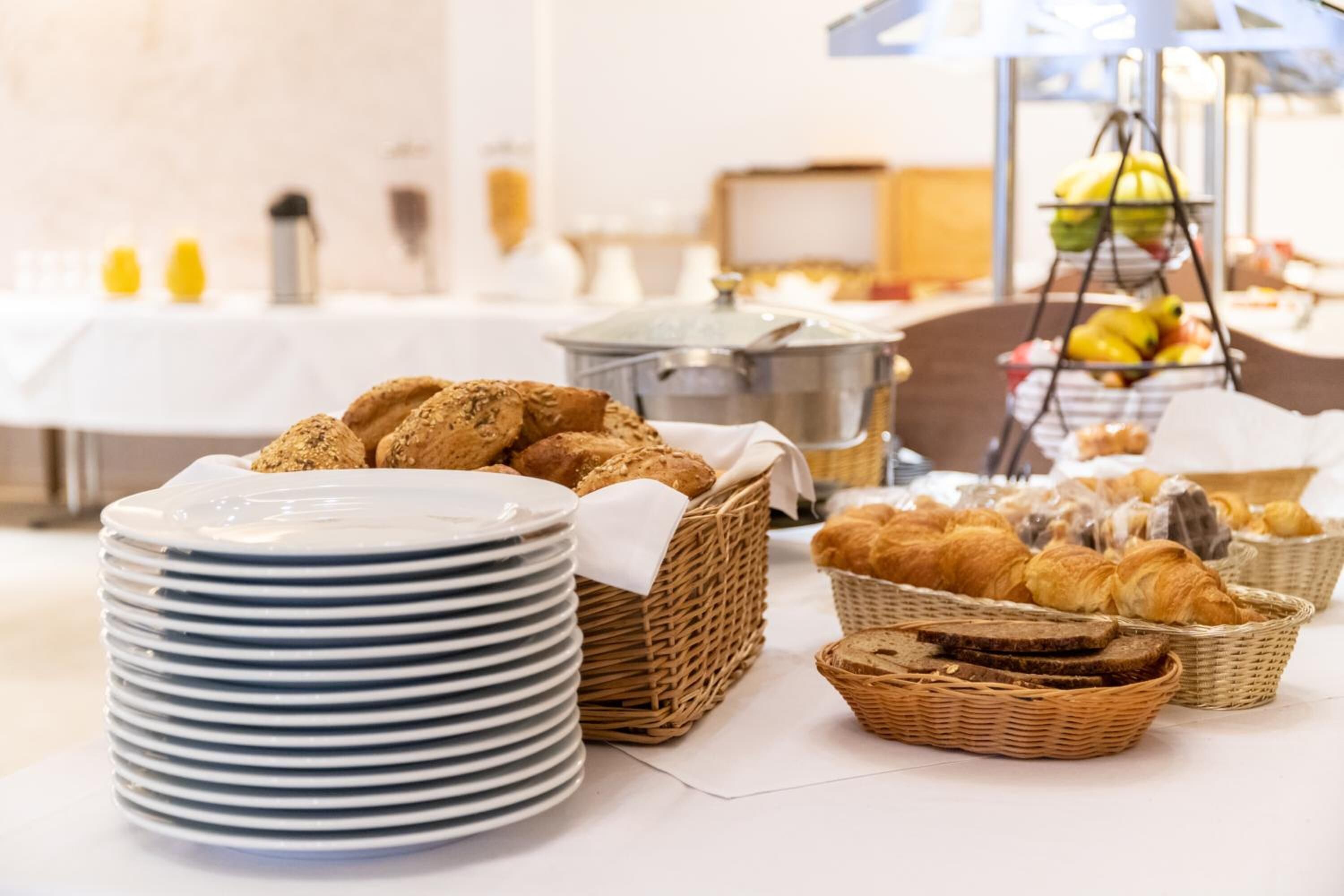 Un bufé de desayuno con pan, bollería y frutas.