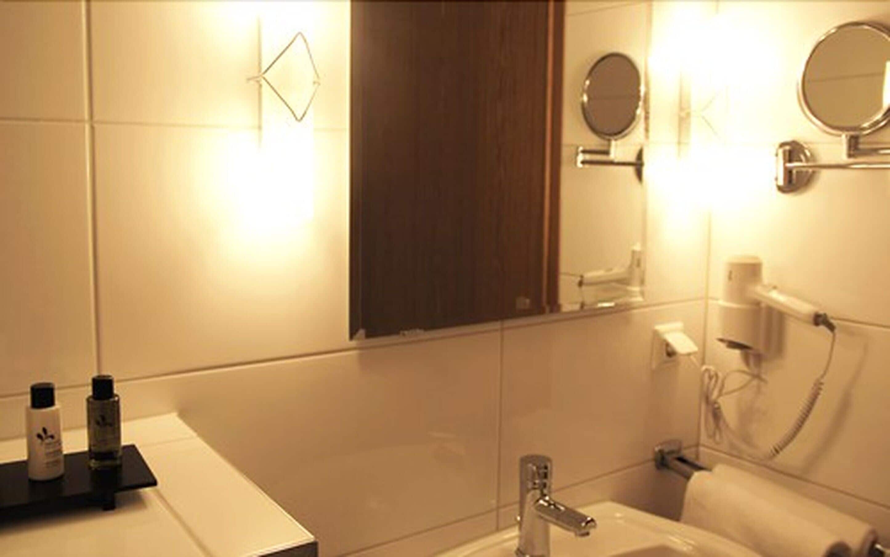 A modern bathroom with a sink, mirror, and towel rack.