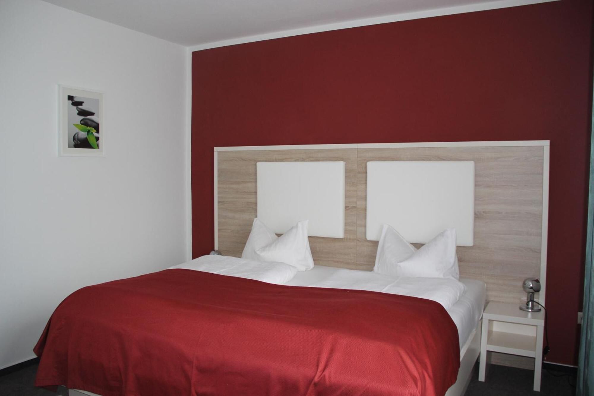 A hotel room with a bed, a nightstand, and a wall-mounted picture.