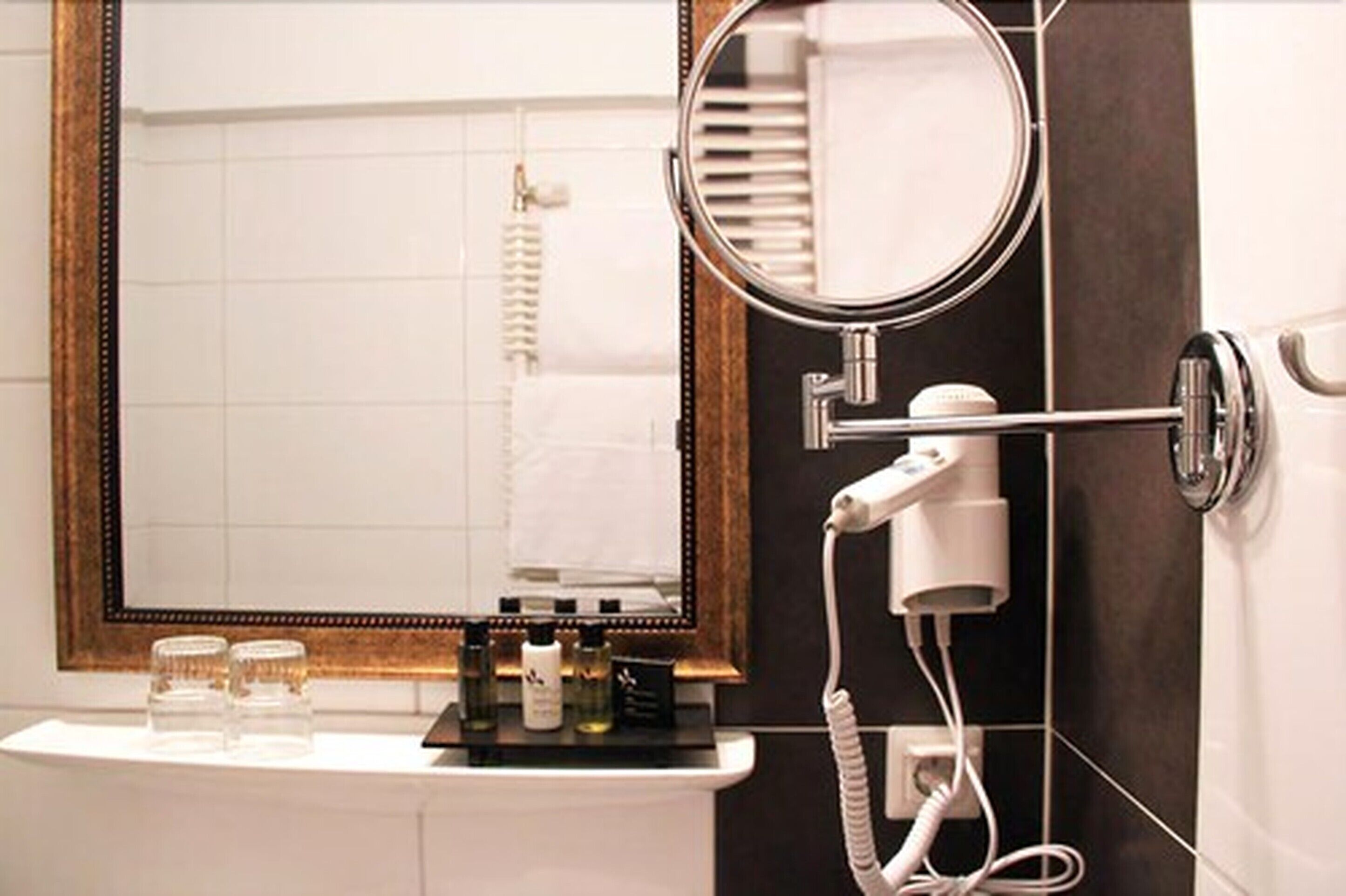 Un bagno con specchio, asciugacapelli e articoli da toilette sul ripiano.