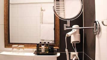 Un bagno con specchio, asciugacapelli e articoli da toilette sul ripiano.