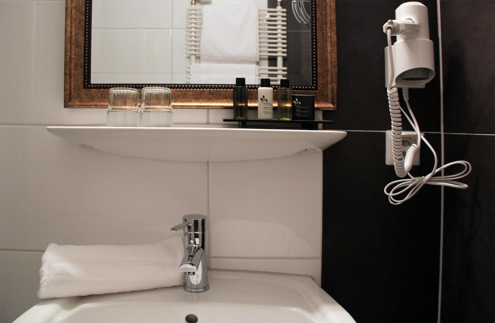 Un baño con lavamanos, espejo y secador de pelo.
