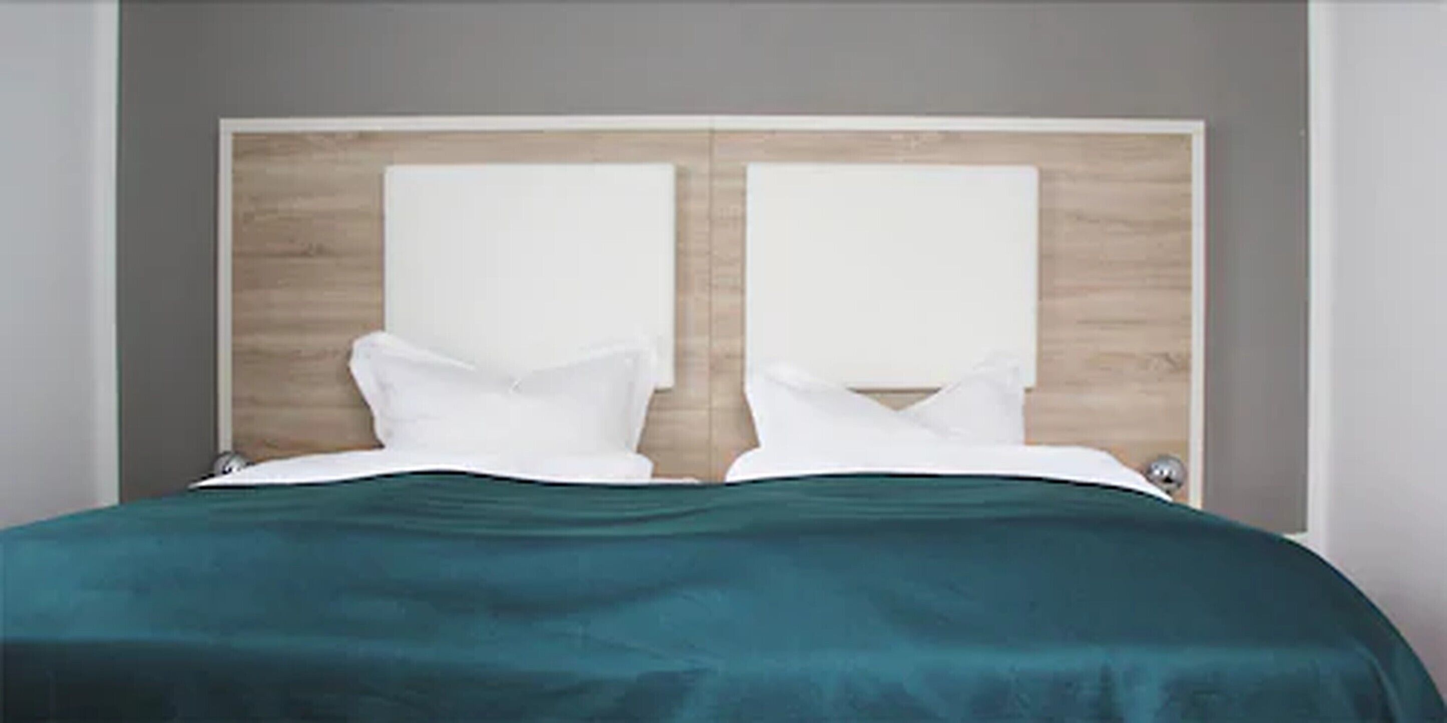 Een bed met een houten hoofdbord en witte kussens.
