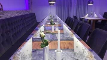 A long dining table with white candles, a floral centerpiece, and a table runner with a pattern.