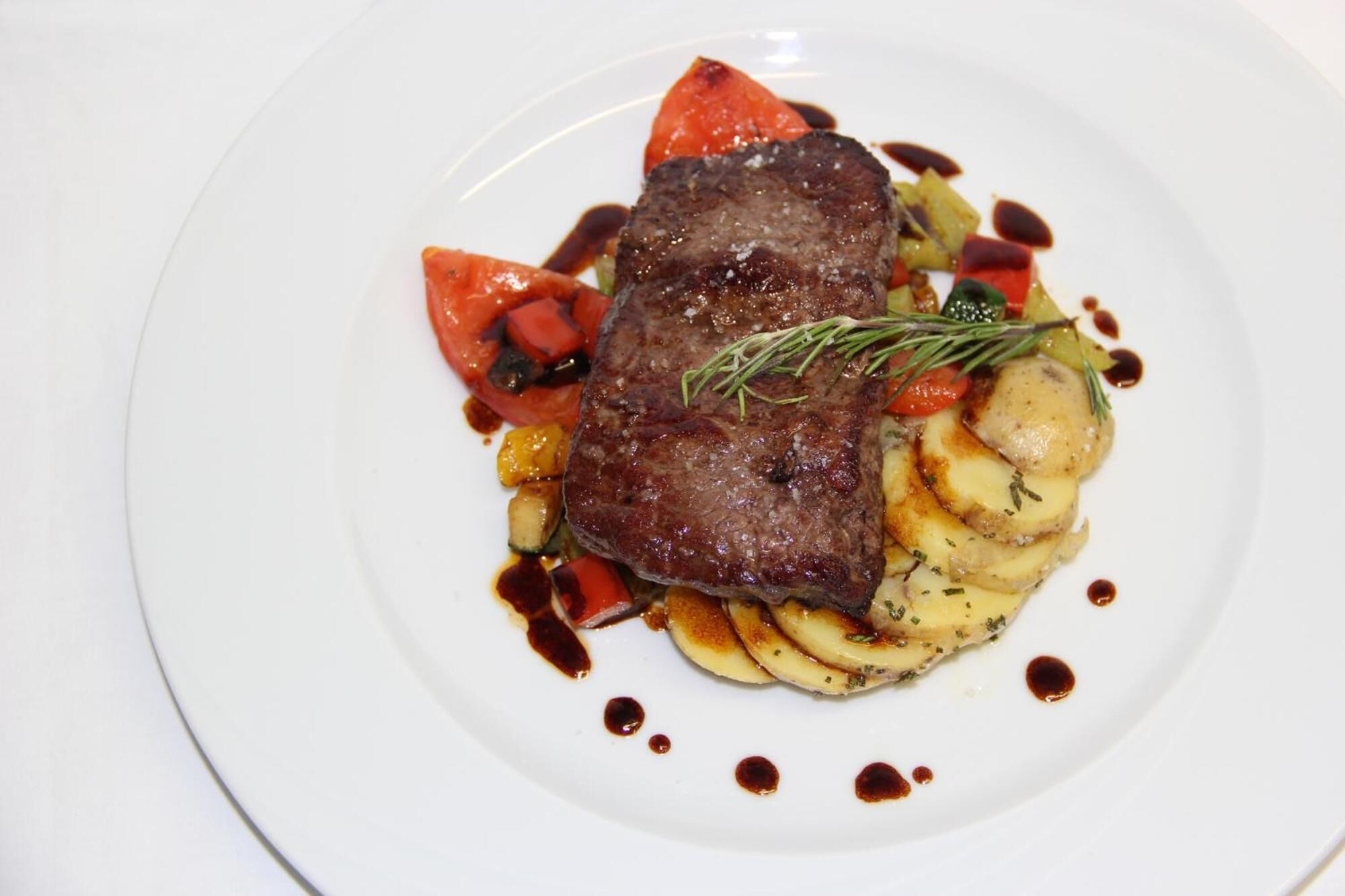 A plate with a steak, vegetables, and sauce.
