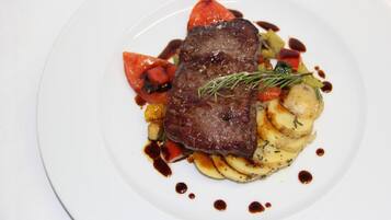 A plate with a steak, vegetables, and sauce.
