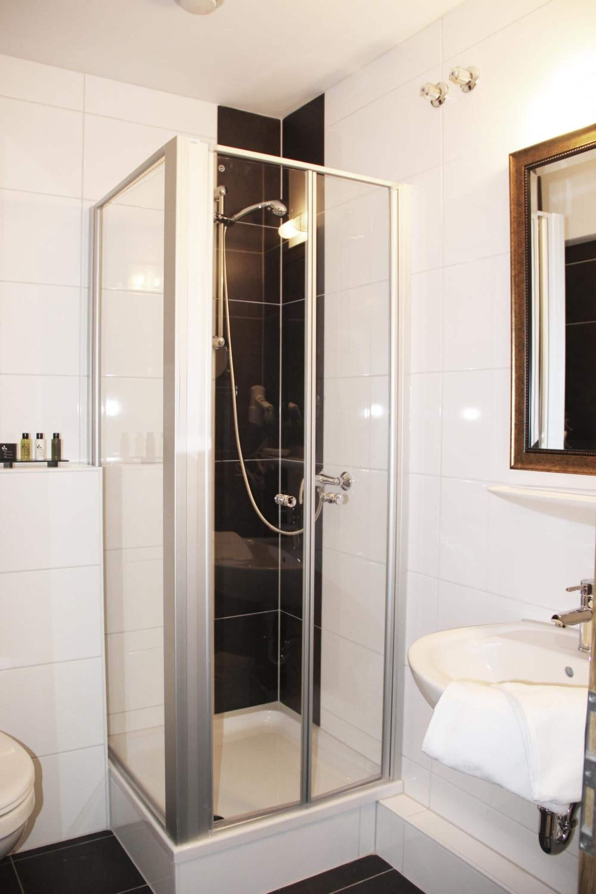 Une salle de bain moderne avec une douche à parois de verre, un lavabo blanc et un miroir au-dessus.