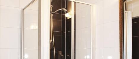 Une salle de bain moderne avec une douche à parois de verre, un lavabo blanc et un miroir au-dessus.