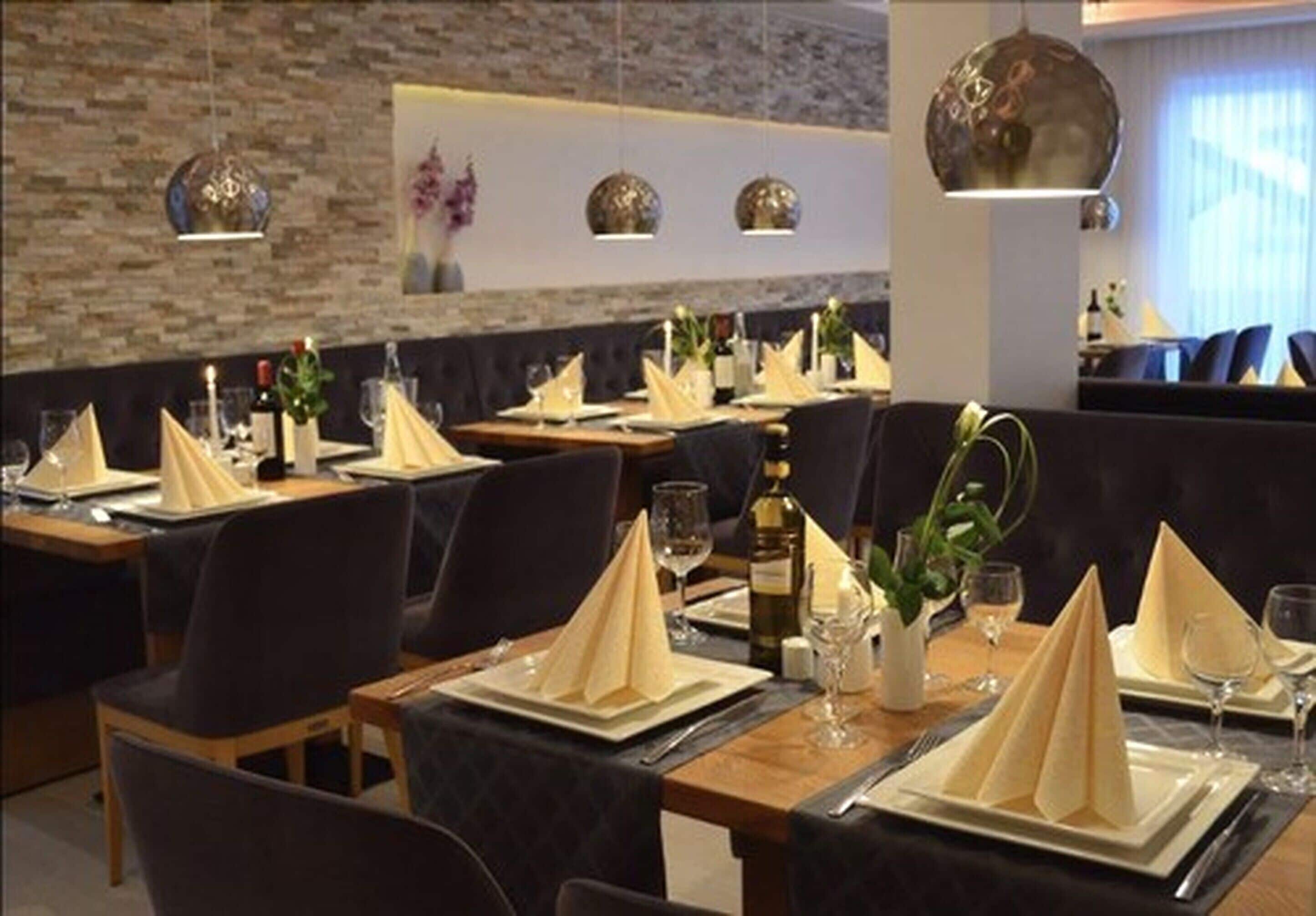 Un restaurante con mesas dispuestas para comer, que presenta una pared de ladrillo e iluminación colgante.