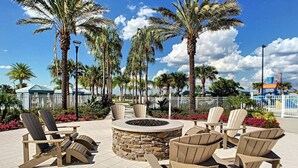 An outdoor seating area with Adirondack chairs and a stone fire pit.