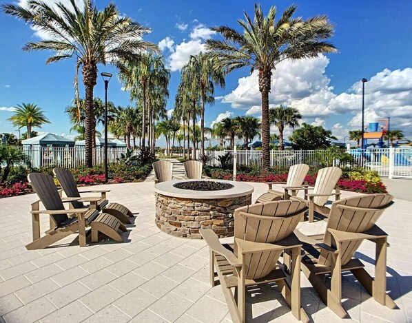 An outdoor seating area with Adirondack chairs and a stone fire pit.