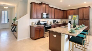 A modern kitchen with wooden cabinets, stainless steel appliances, and a central island with bar stools.