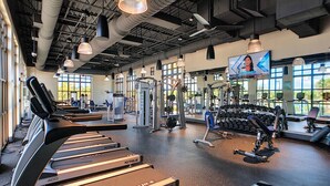A gym with treadmills, weight machines, and dumbbells.