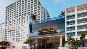 Een modern hotel met een glazen gevel, meerdere verdiepingen en een opvallend entreegebied.