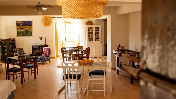 A dining area with a round table and chairs, a ceiling fan, and a bookshelf in the background. - L'Arcadia (Giffoni sei Casali)
