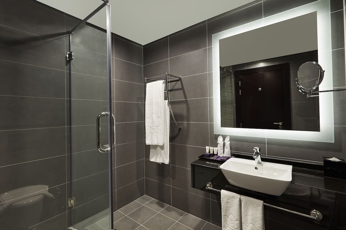 A modern bathroom with a glass-enclosed shower, a large mirror, and a black vanity with a white sink.