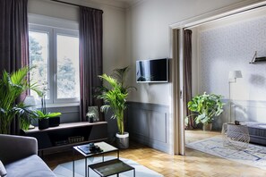 A modern living room with a sofa, coffee table, and potted plants. - Live Life Acropolis (Athens)