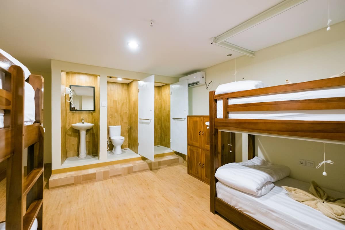 A room with bunk beds, a wooden cabinet, a sink, and a mirror.