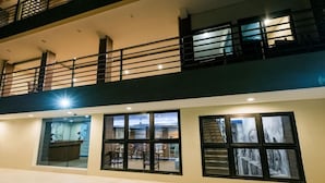 A multi-story building with a balcony, large windows, and a reception area. - Caroline Hostel (Canggu)
