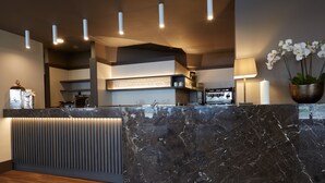 A modern reception area with a marble counter, overhead lighting, and a potted orchid. - DC Hotel International (Padova)