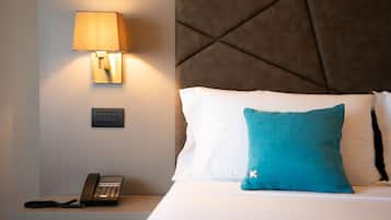 Una camera d'albergo con un letto, una lampada da comodino, un telefono e un interruttore della luce a parete.
