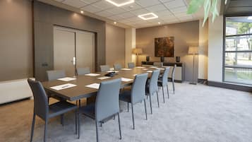 Un salón de conferencias con una mesa larga, sillas y dos lámparas.