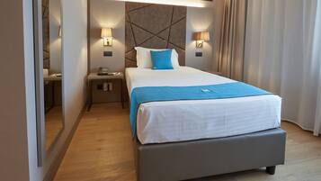 A hotel room with a bed, bedside tables, lamps, and a mirror.