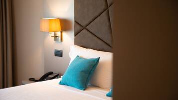 A hotel room with a bed, a bedside lamp, a telephone, and a wall-mounted light fixture.