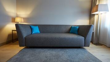Una sala de estar moderna con un sofá gris, dos cojines azules, una lámpara de pie y una alfombra.