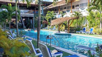 Alberca al aire libre, sombrillas en la alberca y camastros