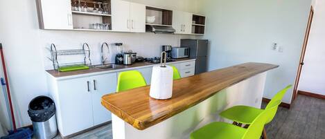 Una cocina moderna con armarios blancos, encimera de madera y una silla verde brillante.