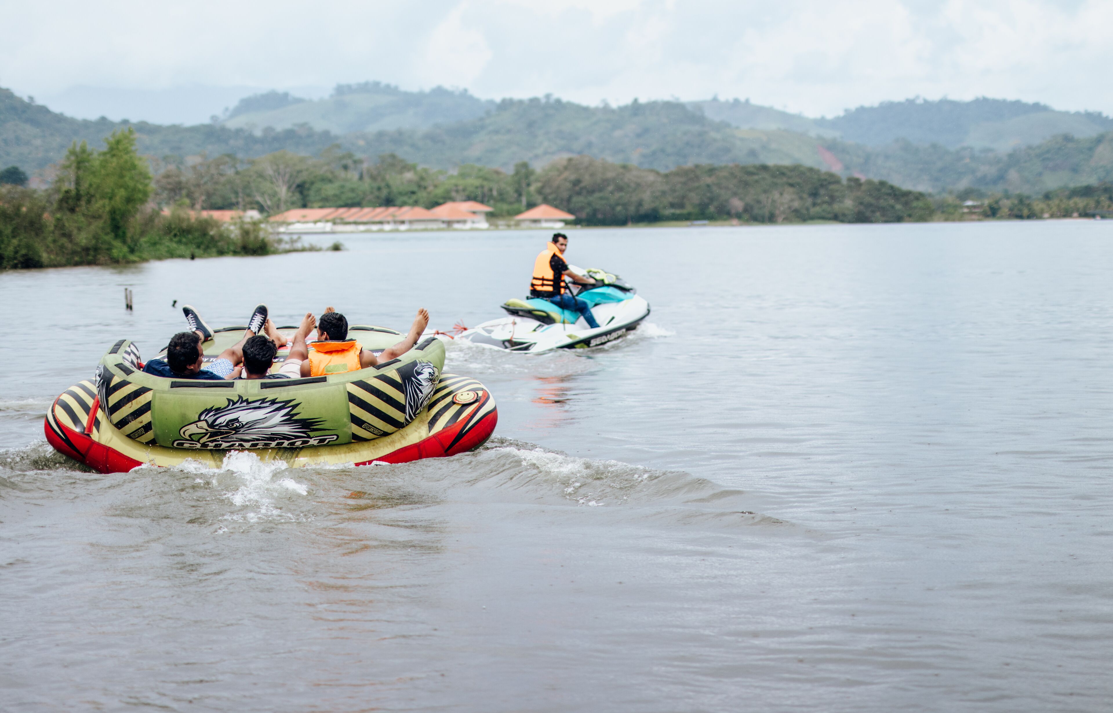 A group of people on a watercraft near a lake with hills in the background.