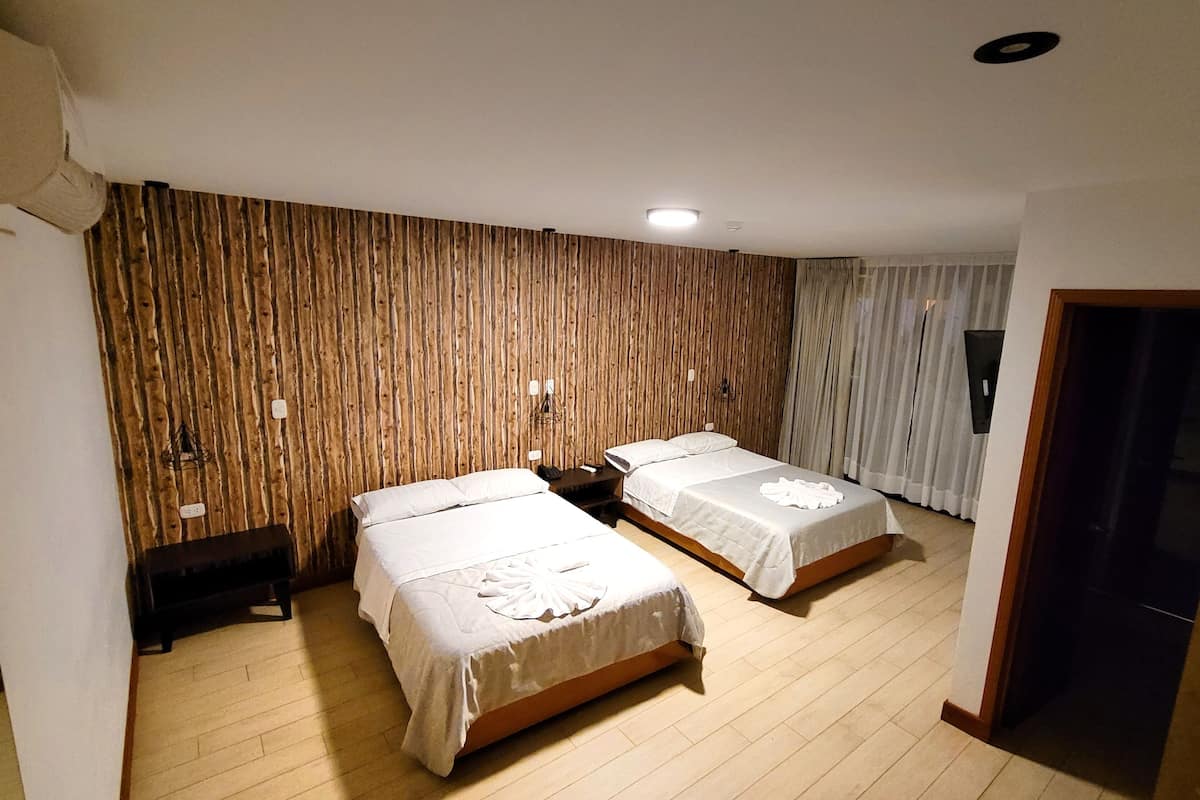 Een hotelkamer met twee bedden, houten paneelwanden, een bankje en een plafondlamp.