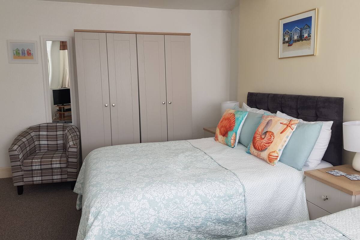 A bedroom with a bed, a wardrobe, a chair, and a painting on the wall.