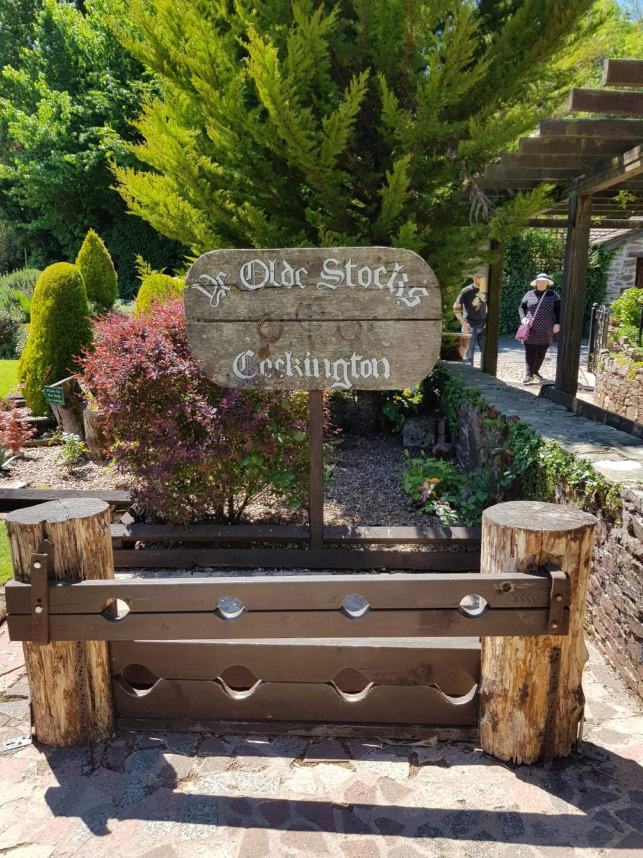 A wooden sign with the text 'Old Stock' and 'Cockington' indicating a location.