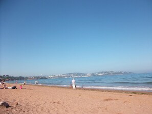 A beach with people, a clear sky, and a distant cityscape. - Rosemead Guest house (Paignton)