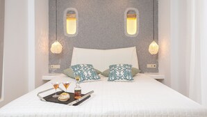 A neatly made bed with a white quilt, two pillows, and a tray with drinks and a bottle. - My Island Home (Naxos)