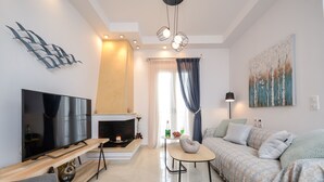 A modern living room with a flat-screen TV, a fireplace, a sofa, and a dining table. - My Island Home (Naxos)