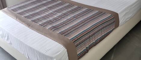 Un dormitorio moderno con una cama grande, cabecera y mesita de noche.