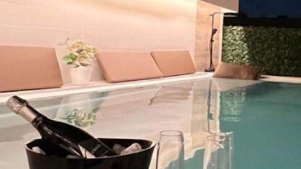 A modern outdoor pool area with a champagne bucket, glasses, and a potted plant. - Palazzo Firenze (Naples)
