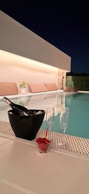 A modern outdoor pool area with a champagne bucket, glasses, and a potted plant. - Palazzo Firenze (Naples)
