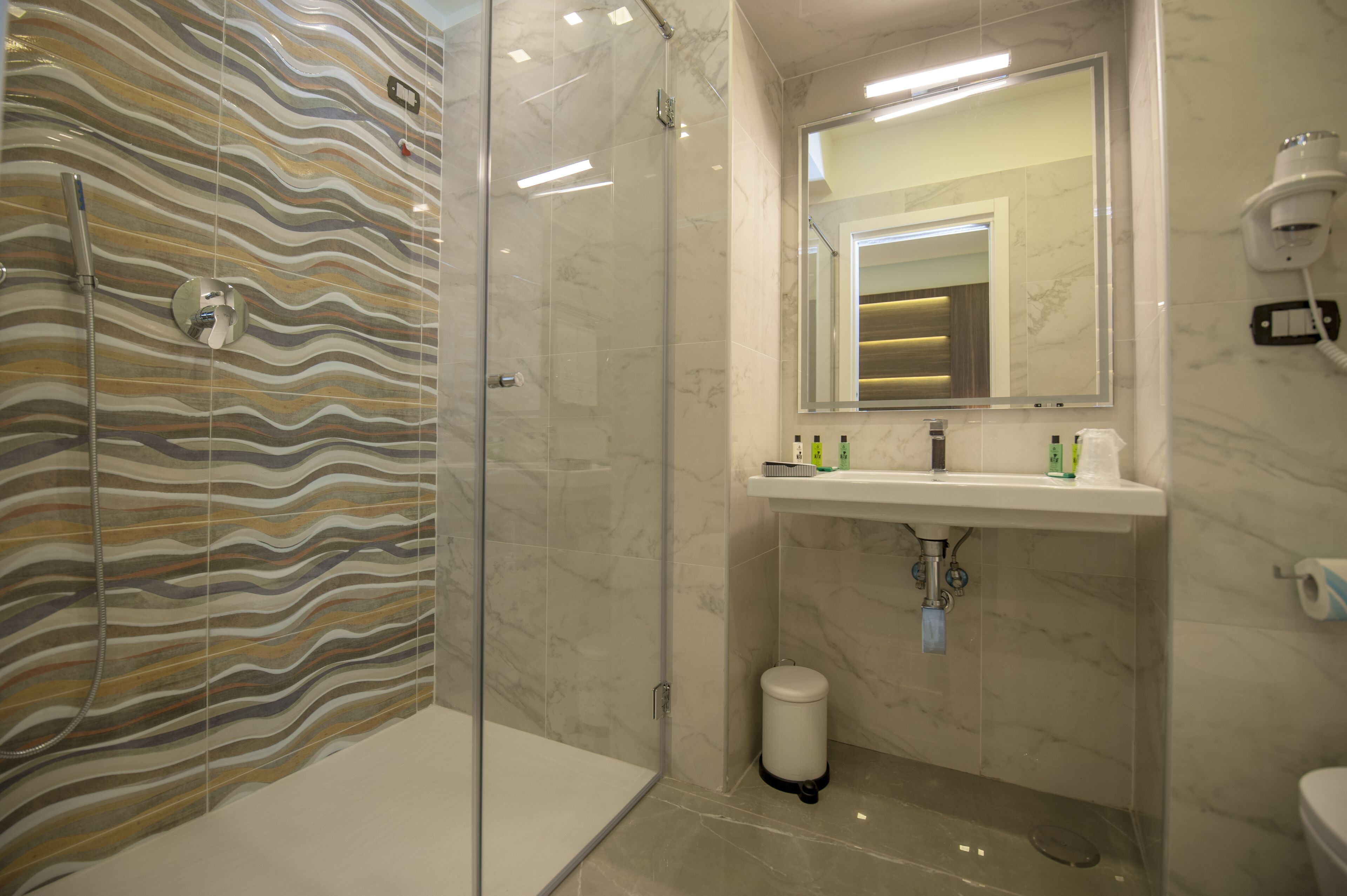 Un baño con ducha, lavamanos y artículos de aseo, y un inodoro.