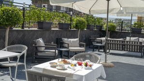 An outdoor seating area with tables and chairs, potted plants, and umbrellas. - Palazzo Firenze (Naples)
