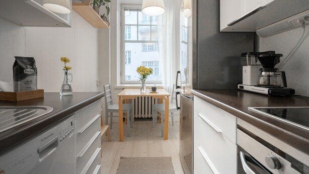 A modern kitchen with stainless steel appliances, a wooden table, and a window with a view. - Roost Kristianinkatu (Helsinki)