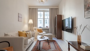 A modern living room with a sofa, armchairs, a coffee table, and a TV. - Roost Kristianinkatu (Helsinki)
