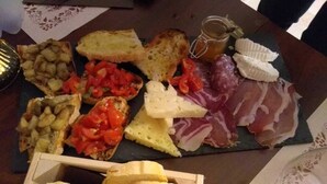 Une planche de charcuterie comprenant différents fromages, des viandes séchées et du pain.